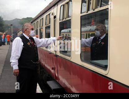 Wansford, UK. 15th Aug, 2020. The Station Master checks one of the carriages, as the Nene Valley Railway have resumed running steam trains from Wansford to Peterborough after the COVID-19 Coronavirus pandemic forced them to stop during lockdown. The 92 Squadron Battle of Britain 34081 steam train has been prepared and is ready to go, with the carriages having their capacity reduced to allow for new social distancing guidelines. Credit: Paul Marriott/Alamy Live News Stock Photo