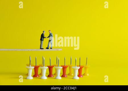 Miniature business concept - two businessman make partnership strategy for risk management transfer Stock Photo