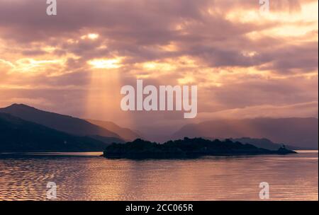 Inner Hebrides, Scotland.  Sunrise as sunrays burst through the clouds lighting up a  mountain range.  Concept: Tranquility. landscape. Space for copy Stock Photo