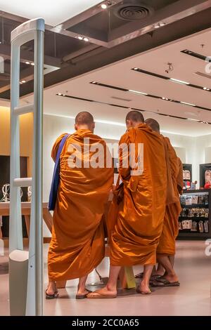 Three Buddhist monks consult each other inside a modern shopping mall in Bangkok, Thailand Stock Photo