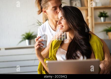 Happy couple in love hugging and using tablet together at home Stock Photo