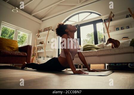 Low angle view of african young woman doing stretching exercise on yoga mat at home Stock Photo
