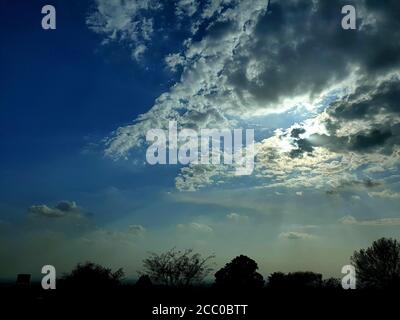 Evening time sun sets world sleeps.Sky blue white and sun trees are also in frame. Beautiful evening.Beautiful sky ever. Stock Photo