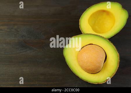 Closeup cut fresh ripe avocado isolated on black wooden table with copy space Stock Photo