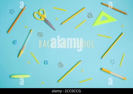 Stationery on blue. Bright stylish flat lay. Different yellow tools with Back to School lettering in centre. Stock Photo