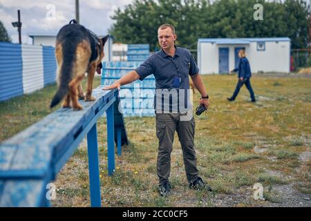 Male security officer training detection dog outdoors Stock Photo