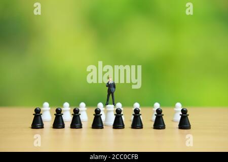 Miniature people strategic concept - businessman standing above chess pawn Stock Photo