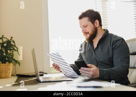 Caucasian manager working with documents, smartphone and laptop. Stock Photo