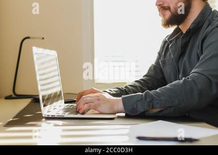 Male bloger writing article on laptop at office. Stock Photo