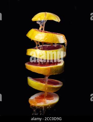 Cut grapefruit flying in the air with juice splashes on a dark black background Stock Photo