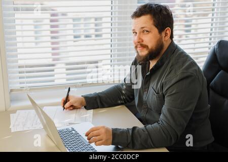 Male financier writing report using laptop at office. Stock Photo