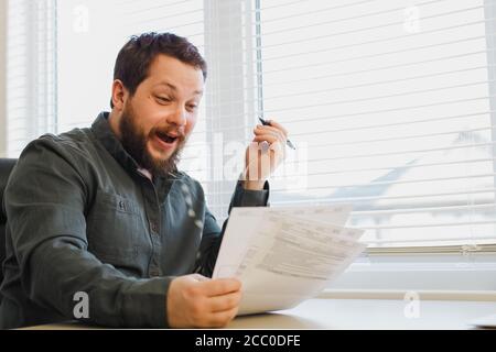 Successful broker reading and filling documents at office near window. Stock Photo