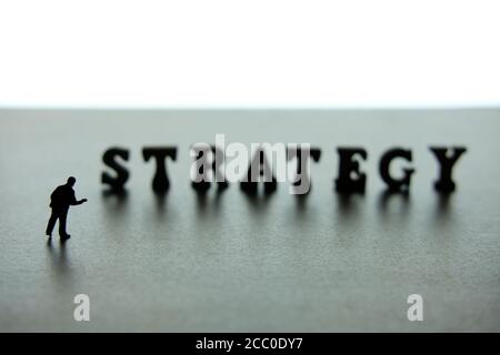 Silhouette of miniature businessmen pointing on strategy word block puzzle Stock Photo