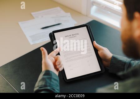 Close up man reading house rental contract on tablet. Stock Photo