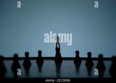 Business strategy conceptual photo - Silhouette of miniature of thinking businessman standing on castle pawn on a chessboard Stock Photo