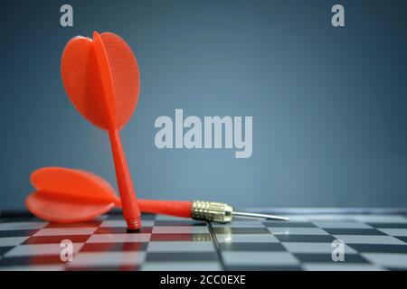 Red dart arrow laying on chess board with dark grey background Stock Photo