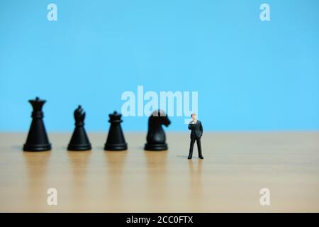 Business strategy conceptual photo - Miniature of businessman standing in front of horse, king, pawn chess piece thinking for solution