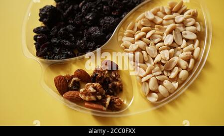 Top closeup view of delicious nuts in plastic transparent containers on yellow background Stock Photo