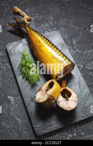 slices of smoked fish mackerel or scomber on black stone table Stock Photo