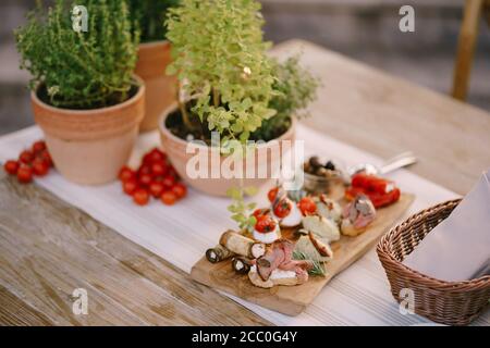 Red tomatoes on a table with a cutting board and flowers in pots. Stock Photo