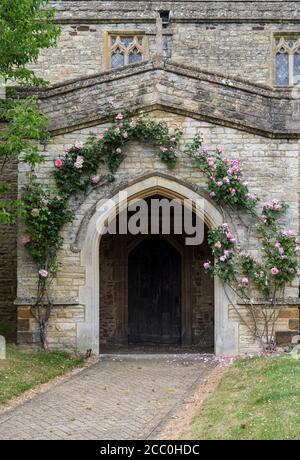 Rambling roses growing around the main door to the church of St Mary The Virgin, Podington, Bedfordshire, UK Stock Photo