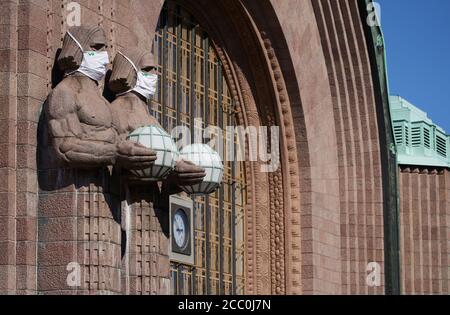 Helsinki, Finland - 16 August 2020: Iconic stone men statues by the side of the entrance to the Helsinki Central Railway Station decorated as wearing Stock Photo