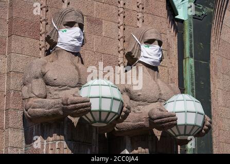 Helsinki, Finland - 16 August 2020: Iconic stone men statues by the side of the entrance to the Helsinki Central Railway Station decorated as wearing Stock Photo