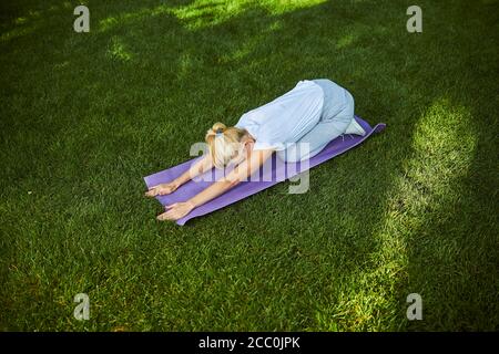 Blonde woman practicing yoga on sunny day in park Stock Photo