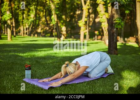 Sporty woman practicing yoga on sunny day in park Stock Photo