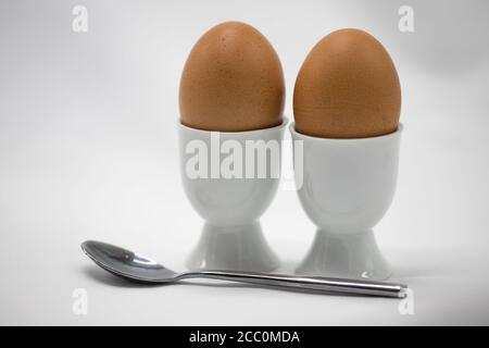 Boiled eggs in egg cups with a spoon Stock Photo
