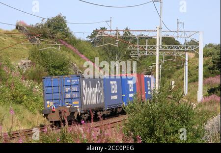 Container train from Daventry to Mossend passing Tebay and starting the climb to Shap Summit on the WCML in Cumbria on Saturday 15th August 2020. Stock Photo