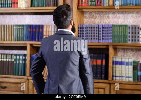 Back view, man near multi colored bookshelf in library. Education, Knowledge, Bookstore, Lecture. Stock Photo