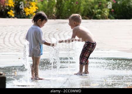 Children play in the water fountains in Priory Street, Coventry. The fountains situated between the university, Cathedral and Herbert art gallery rise and fall and are a feature of the city centre. Coventry is to become city of culture in 2021. Stock Photo