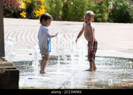 Children play in the water fountains in Priory Street, Coventry. The fountains situated between the university, Cathedral and Herbert art gallery rise and fall and are a feature of the city centre. Coventry is to become city of culture in 2021. Stock Photo