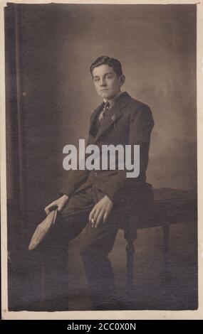 Vintage black and white photo of a young man in suit and tie holding a cigarette. Stock Photo