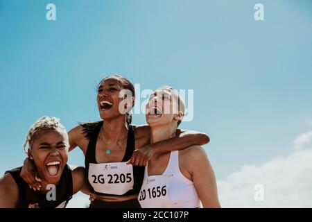Young team of female athletes standing together and screaming in excitement. Diverse group of runners enjoying victory. Stock Photo