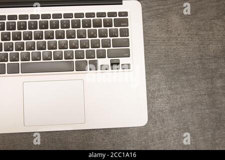 Part of the laptop keyboard on a black wooden table. Workplace. Top view Stock Photo