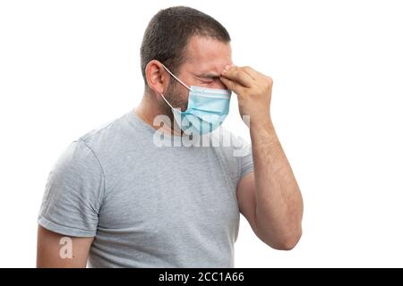 Adult man wearing medical or surgical mask having headache symptom touching forehead with fingers as focused stress thinking concept isolated on white Stock Photo