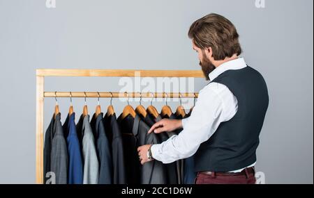 Man picking suit from personal wardrobe, tailored clothes concept. Stock Photo