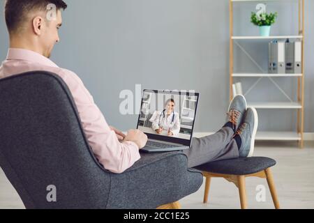 Young guy working with laptop computer at home office, mockup for design. Student participating in online webinar Stock Photo