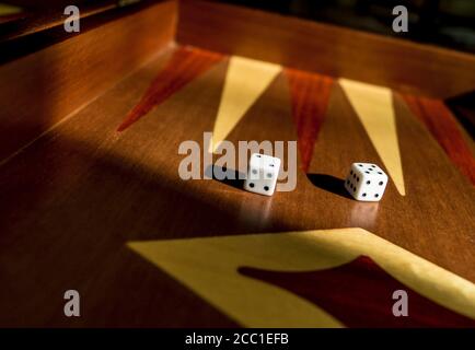 Two dice on backgammon game - traditional old board game. Beautiful old elegant mahagoni wood game Stock Photo