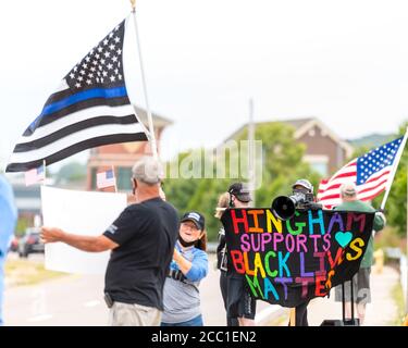Black Lives Matters protestors holding signs and yelling on a megaphone at people holding a Thin Blue Line flag supporting local police. Stock Photo