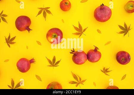 Pattern of pomegranate fuits with fall leaves isolated on yellow background. Food background. Flat lay, top view Stock Photo
