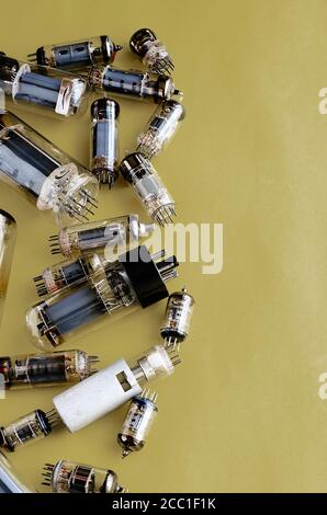 Random vacuum tubes on a yellow background. A group of radio tubes of different sizes and purposes. Copy space. Selective focus. Stock Photo