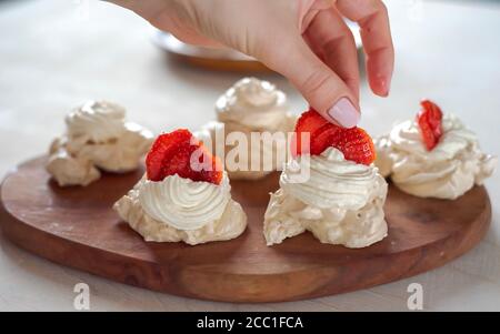 the process of creating Pavlova dessert, decorating the meringue with cream from the culinary bag Stock Photo