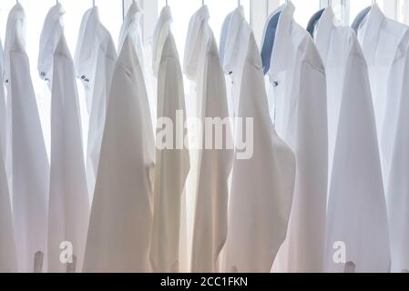 white men's shirts hang on the shoulders in the closet Stock Photo