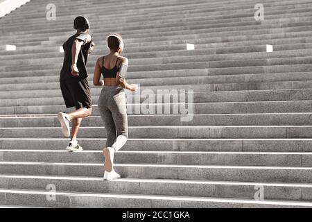 Urban Sport. Black Man And Woman Running Up Steps In City Park Stock Photo