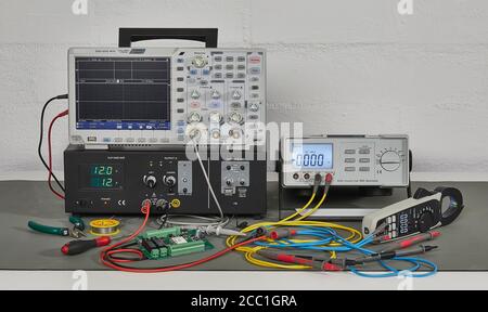 Laboratory equipment, including oscilloscope and multimeter, on a worktable, showing colored cable spaghetti Stock Photo