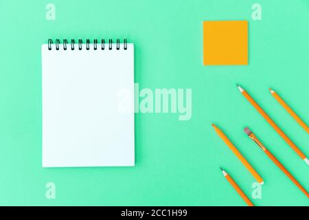 Open a blank notepad on the spiral and office and school supplies on green background. Copy space, flat lay. Back to school concept. Stock Photo