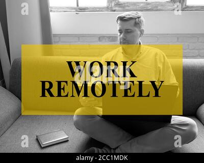 Work remotely concept. A man is sitting on the couch and working on a laptop. Stock Photo